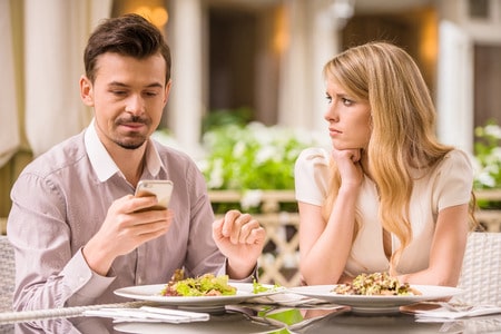 40650724 - young smiling couple in gorgeous restaurant. man looking at phone.